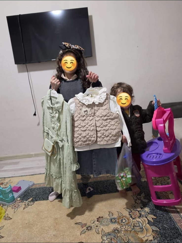 Kendilerine ulaştırılan kıyafetleri gösteren iki çocuk