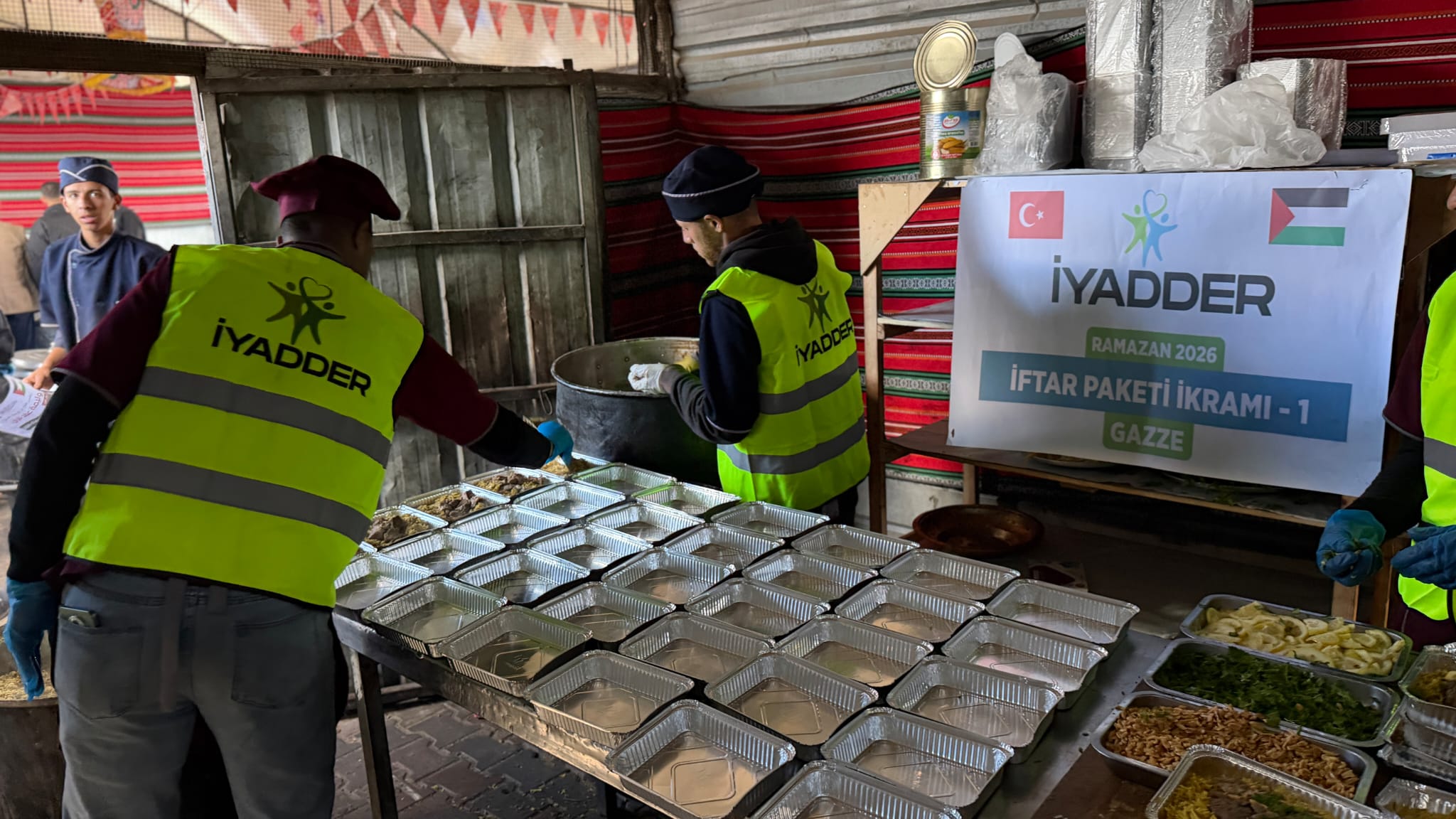 Gazze'de yemeği alüminyum kaplara paylaştıran İYADDER gönüllüleri