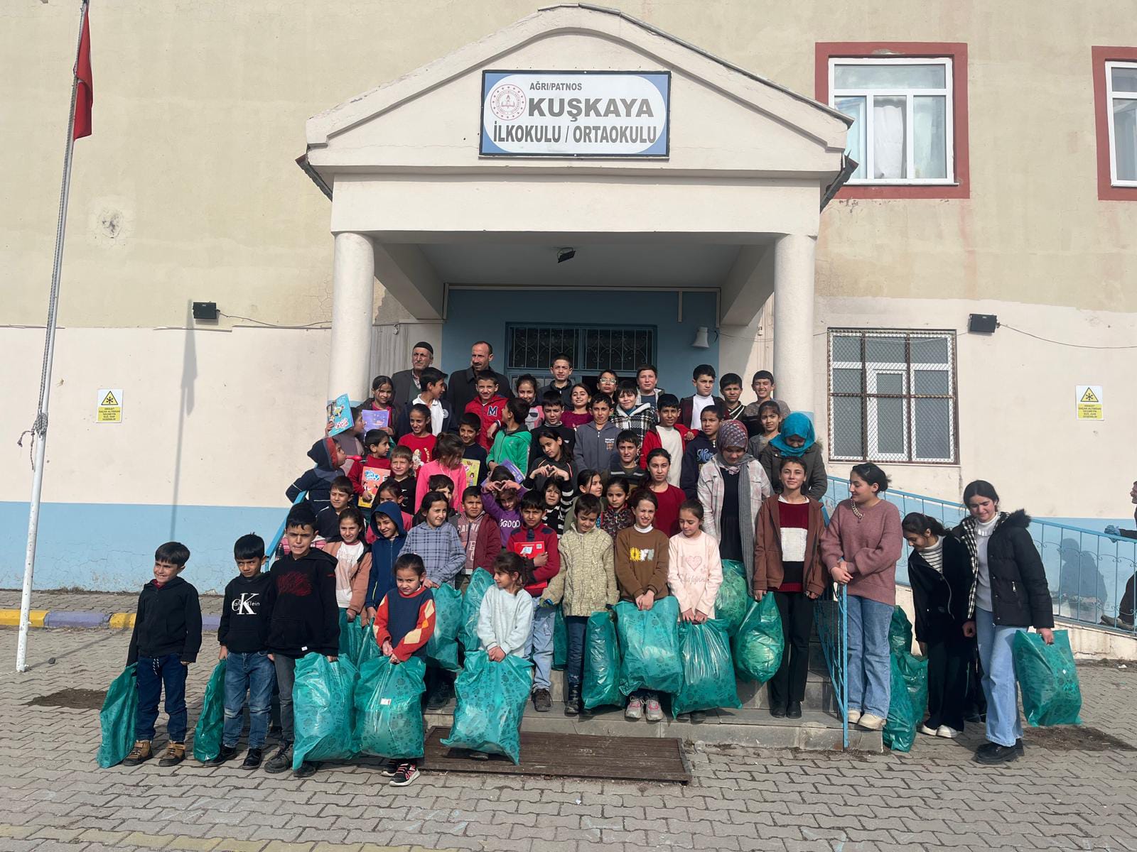 Okul girişinde yardım paketleriyle poz veren öğrenci grubu